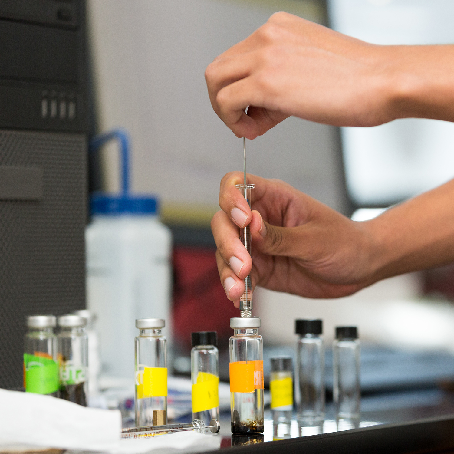pair of hands holding a syringe, collecting a sample